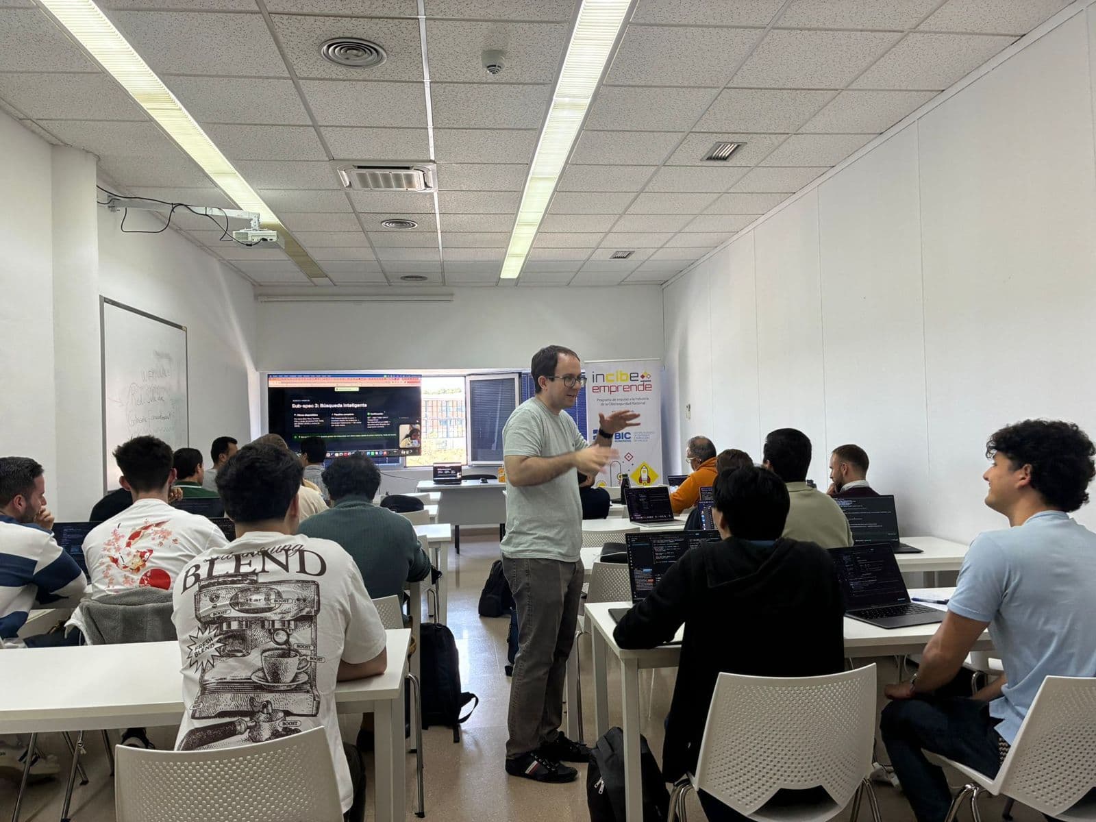 Aula completa durante un workshop presencial, con el código proyectado en pantalla